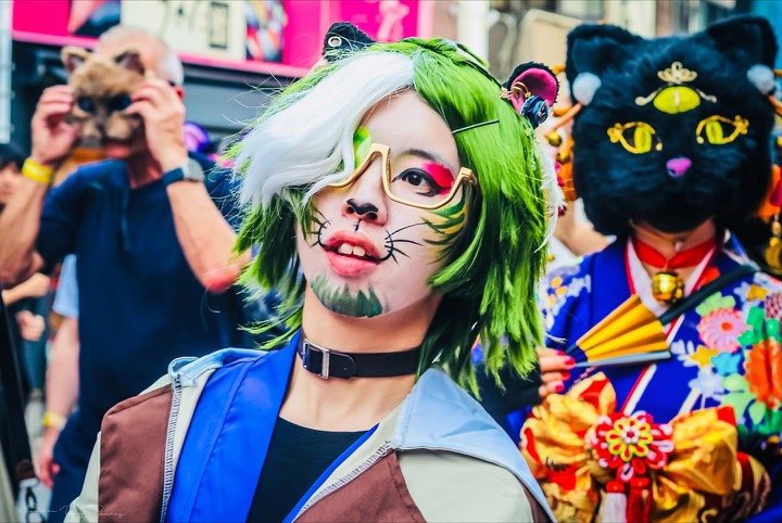 Street portrait of a cosplayer with green hair and cat-whisker makeup in Tokyo